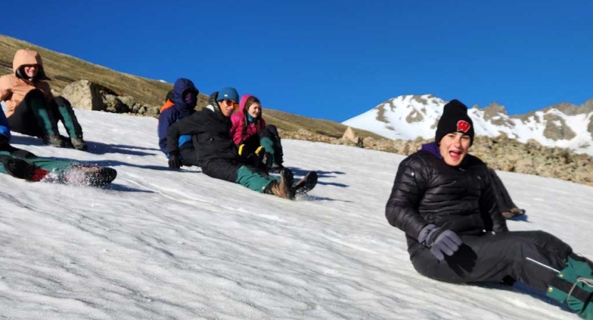 a group of people slide down a snowy incline